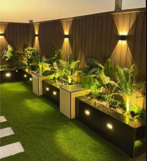 أحواض زرع داكنة بإضاءة سفلية على عشب صناعي ليلًا